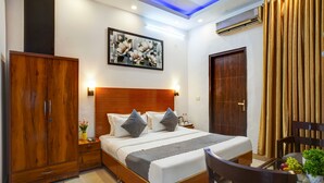 Una habitación de hotel con una cama de madera, un armario, una mesita de noche con una lámpara y un cuadro en la pared.
