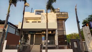 Un hotel moderno con fachada plana, una escalera que lleva a la entrada y un camino de acceso con puerta.