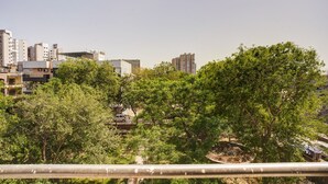 Un paisaje urbano con edificios modernos, cielo despejado y árboles verdes frondosos en primer plano.