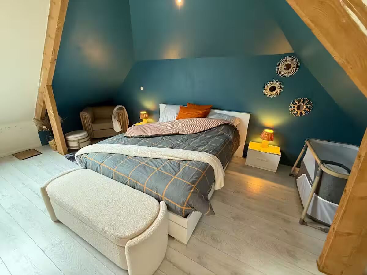 Ein Schlafzimmer mit Bett, Nachttischen, einer Bank und Wandbildern.