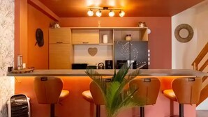 Una cocina moderna con una isla central, taburetes de bar y una decoración con forma de corazón en la pared.