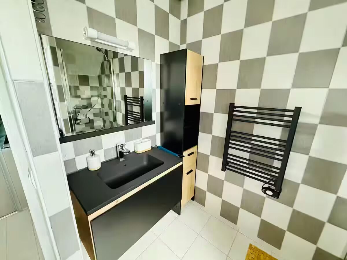 A modern bathroom with a black sink, a mirror, and a towel rack.