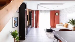 Una sala de estar moderna con una escalera, un comedor y vistas al exterior.