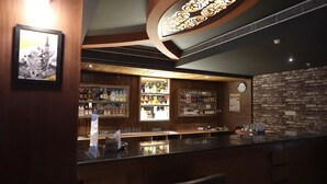 Un área de bar con paneles de madera, un reloj y estantes llenos de botellas.