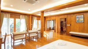 A spacious room with wooden flooring, a bed, a sofa, and a bench. - Vanasin Residence (Tak)
