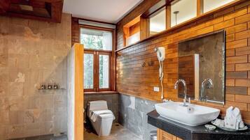 Un baño moderno con diseño de pared de madera, un espejo grande, un lavamanos y un inodoro.