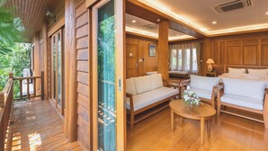 A wooden-floored room with a sofa, two chairs, and a small table. - Vanasin Residence (Tak)
