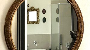 A bathroom with a large oval mirror, a sink, a shower, and a toilet. - La Casa Dell'Artista - Short Term Rentals - Ferla (Ferla)