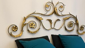 A bed with teal pillows and a decorative metal headboard with floral and scroll designs. - La Casa Dell'Artista - Short Term Rentals - Ferla (Ferla)