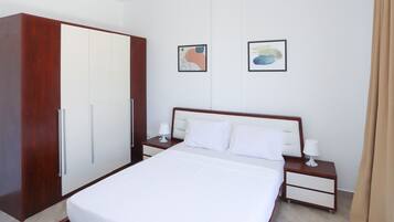 A hotel room with a bed, nightstands, a wardrobe, and two framed artworks on the wall.