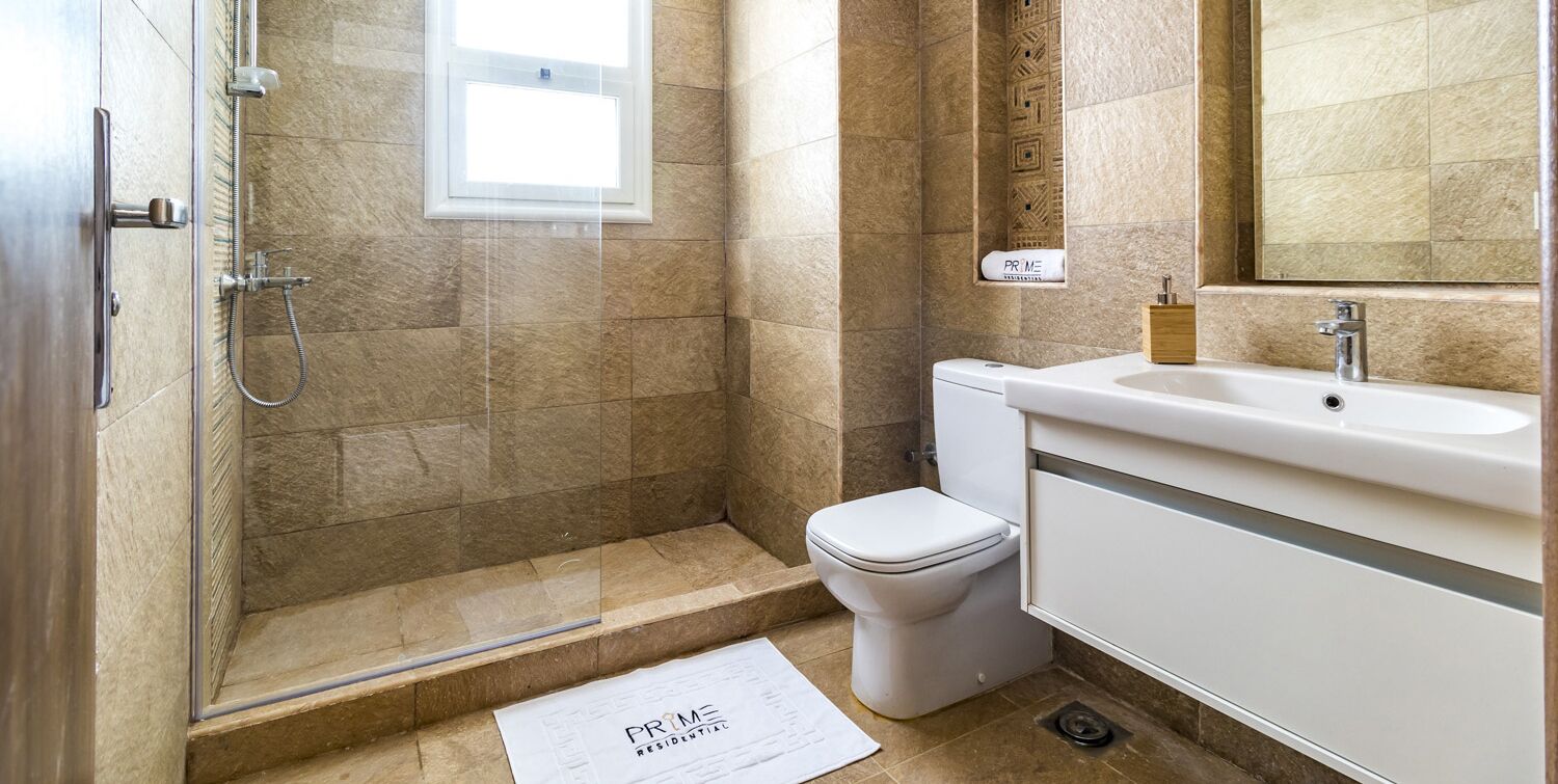 A bathroom with a shower, toilet, sink, and a towel rack.