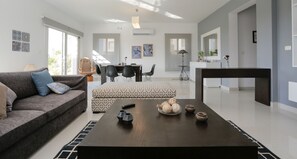 A modern living room with a sofa, a coffee table, and a dining area with chairs and a table.