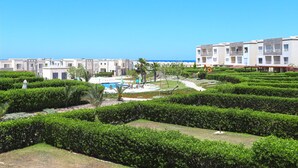 A resort with a pool, manicured gardens, and buildings with balconies. - Prime Holidays Amwaj (El Alamein)