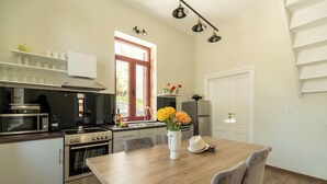 A modern kitchen with stainless steel appliances, a wooden dining table, and a window with a view. - Casa Chris (Chania)