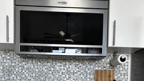 A modern kitchen with a Maytag microwave, a tiled backsplash, a knife block, and wooden cabinets. - Peaceful Villa near beaches to enjoy El Poblado de Boqueron. Pet-Fiendly. (Boquerón)