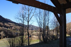 Una estructura de madera rústica con vistas a un paisaje montañoso y árboles sin hojas.