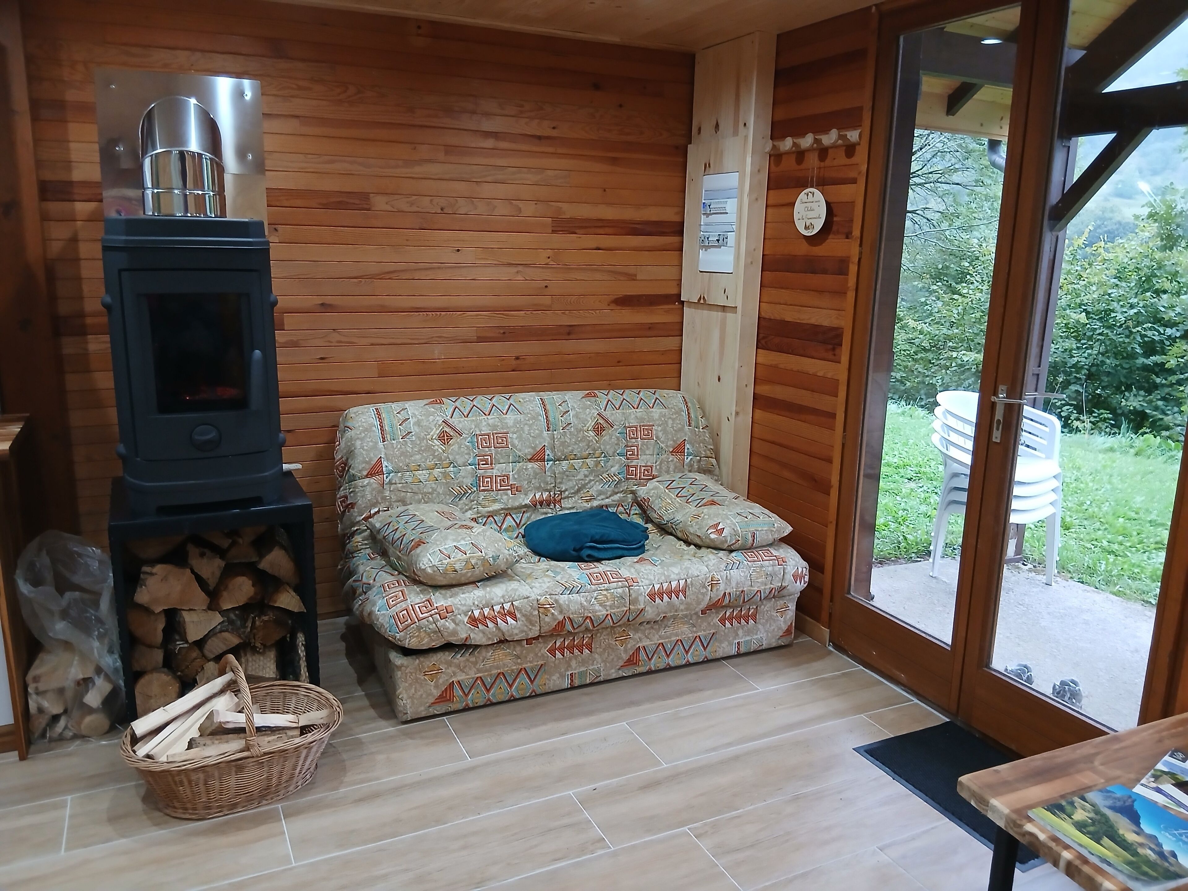 A cozy room with a sofa, a wood-burning stove, and a view of the outdoors.