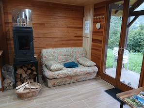 Une pièce chaleureuse avec un canapé, un poêle à bois et une vue sur l’extérieur.