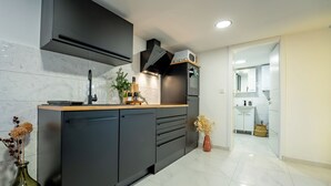 Una cocina moderna con armarios oscuros, una campana extractora de acero inoxidable y un salpicadero de azulejos blancos.