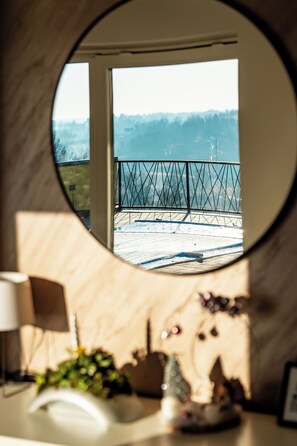 Enjoy the serene view from the balcony, surrounded by lush trees and a clear sky.