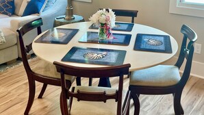 A dining area with a round table, chairs, and a vase with flowers. - Palm Cottage, at Magnolia Court Suites (Beaufort)