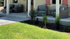 A house with a covered porch, two sofas, and a small table. - Palm Cottage, at Magnolia Court Suites (Beaufort)