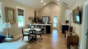 A spacious living area with a dining table, a sofa, and a kitchen in the background. - Palm Cottage, at Magnolia Court Suites (Beaufort)