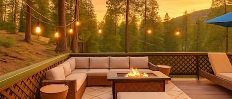 An outdoor deck with a sofa, a fire pit, and string lights.