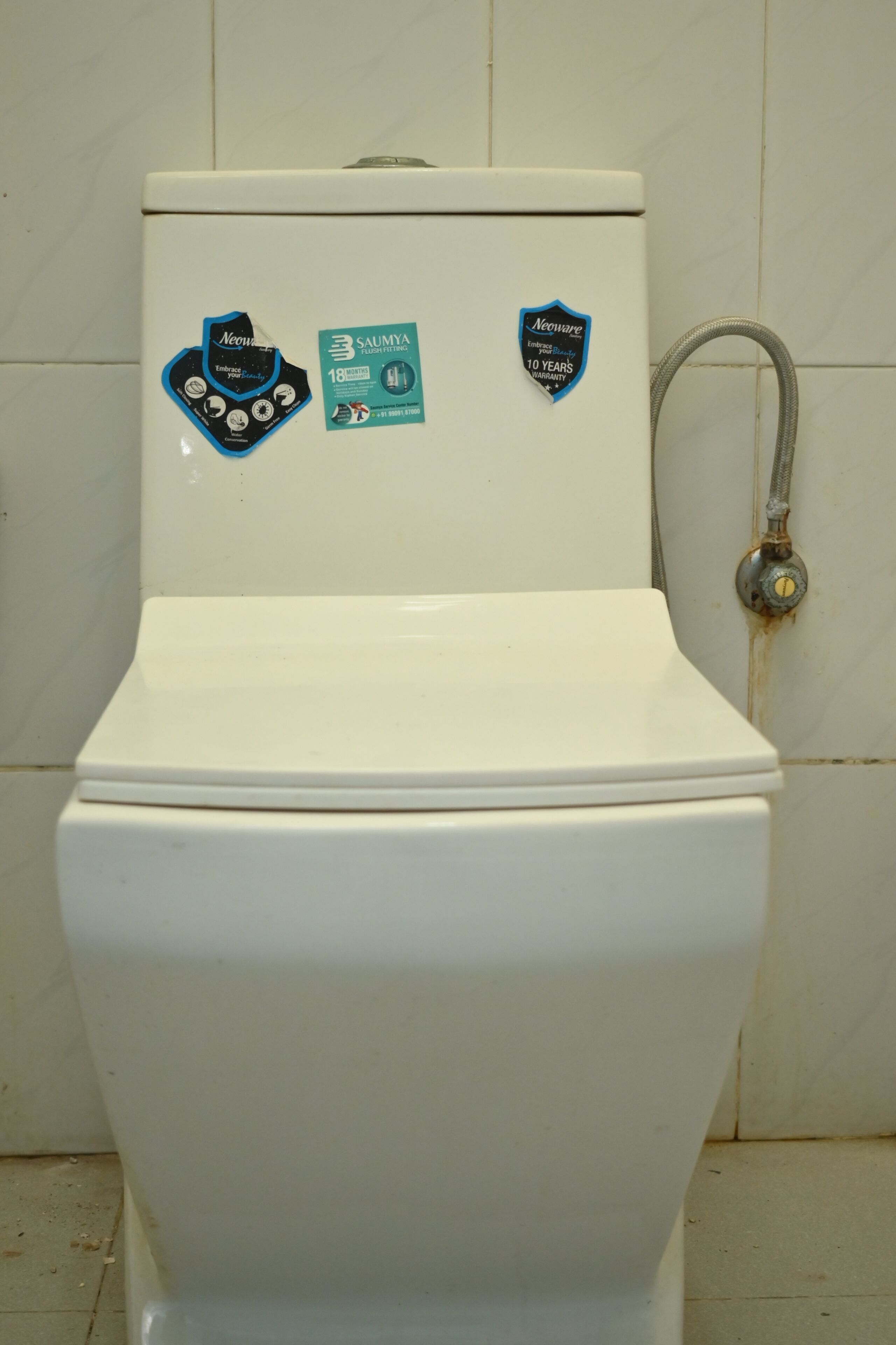 A toilet with two stickers on the tank.