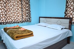 Relax in a cozy room with a neatly made bed, featuring a white bedspread and a folded blanket with a floral pattern.