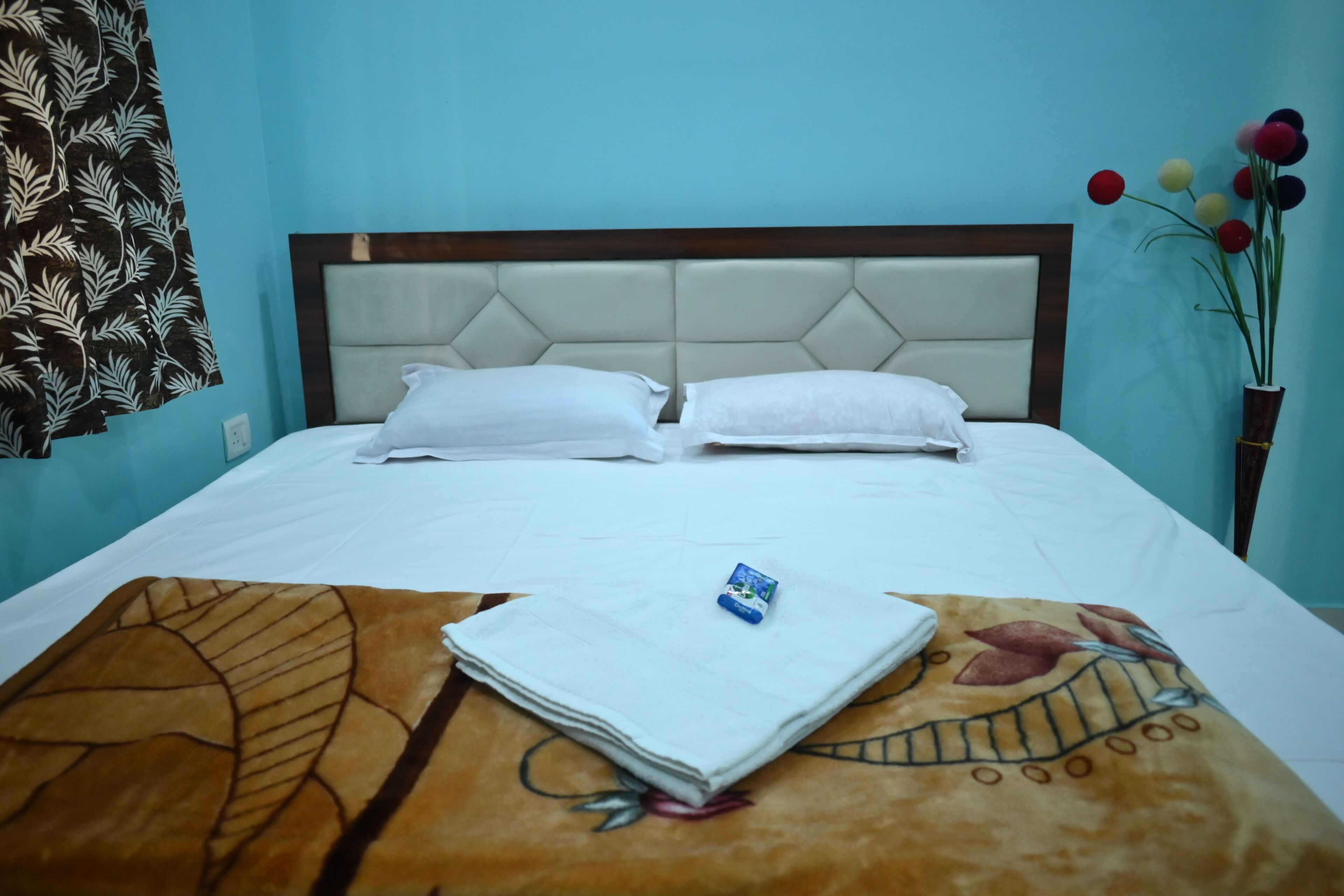 A neatly made bed with white linens, a folded towel, and a small item on the bed.