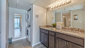 A modern bathroom with a large mirror, built-in sink, and a washing machine.