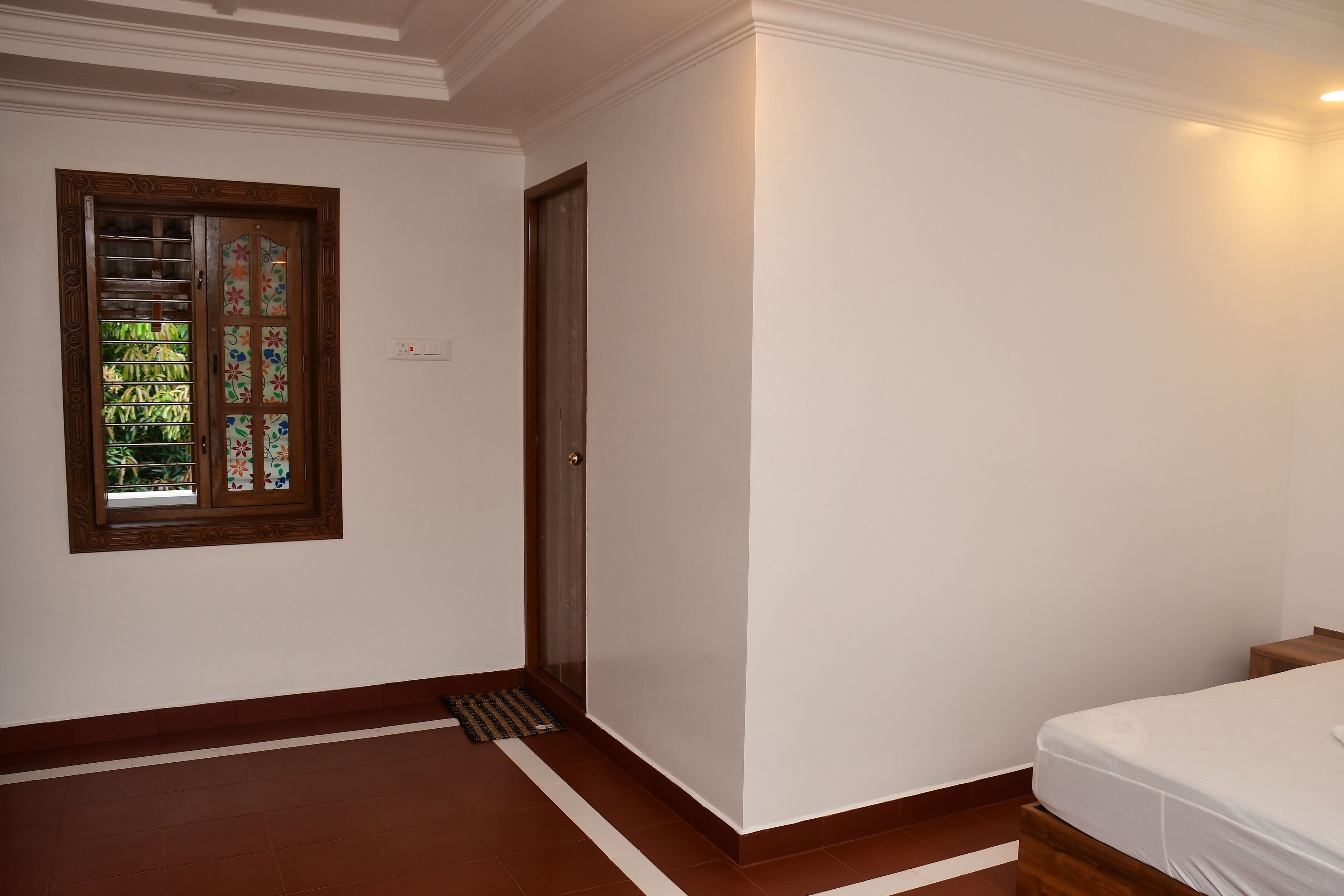 A bedroom with a bed, a door, and a window with a decorative frame.