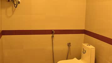Un baño pequeño con inodoro, ducha y calentador de agua instalado en la pared.