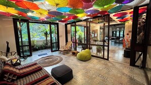 Een kamer met een patroon vloer, een bank, een gele relaxfauteuil en een glazen deur die naar buiten leidt.