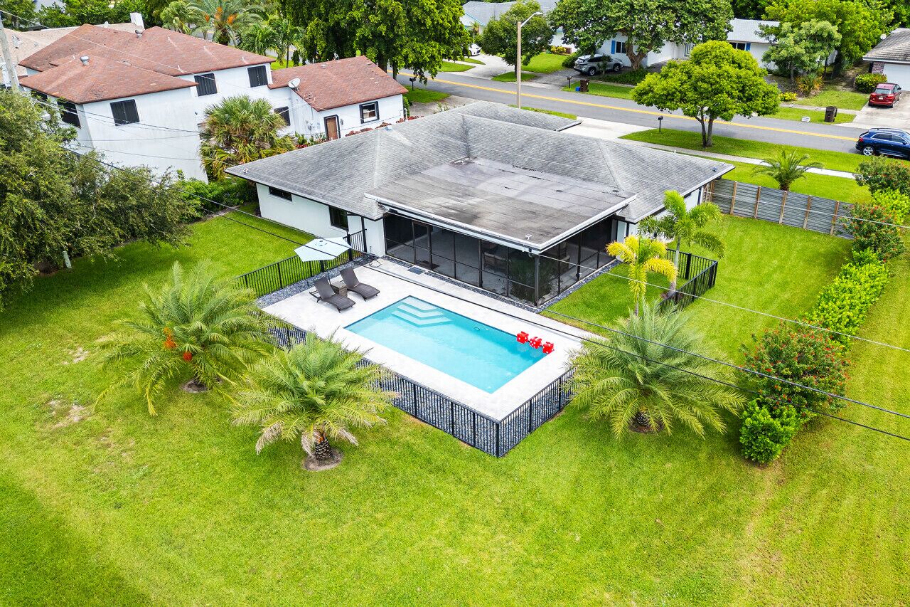 Una moderna casa con piscina, immersa nel verde e circondata da palme.