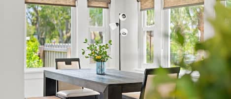 A dining area with a wooden table, chairs, and a vase with flowers.