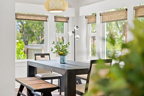 A dining area with a wooden table, chairs, and a vase with flowers.