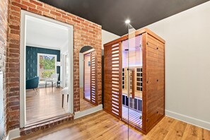 A hallway with a brick wall, a wooden door, and a glass partition.