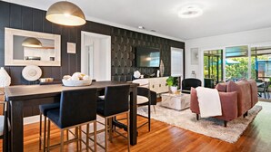 A modern kitchen with dark wood cabinets, a central island, and pendant lighting. - Pool Home w/ Game Room | Near Peanut Island (West Palm Beach)