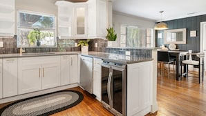 A modern kitchen with white cabinetry, a built-in oven, and a dining area with a black table and chairs. - Pool Home w/ Game Room | Near Peanut Island (West Palm Beach)