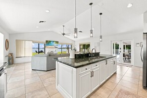 Una cocina amplia con una isla grande, luces colgantes y vistas al exterior.