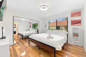 Ein modernes Schlafzimmer mit einem großen Bett, einem Spiegel und Blick ins Freie.