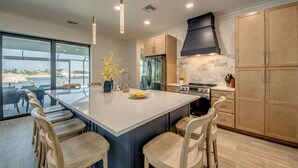 Una cocina moderna con una isla grande, electrodomésticos integrados y vistas al exterior.