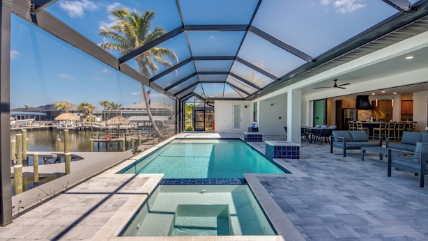 Piscina con paredes de vidrio y vistas al puerto deportivo, mobiliario exterior y ventilador de techo.