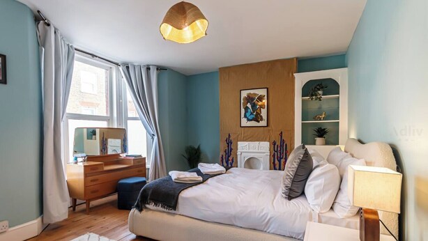 Un dormitorio moderno con cama, mesita de noche, cómoda y chimenea.