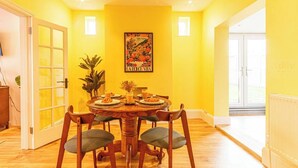 Un comedor con una mesa redonda, sillas y un cuadro en la pared.