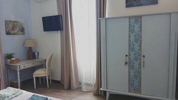 Un dormitorio con cama, escritorio, silla, armario y televisor en la pared.
