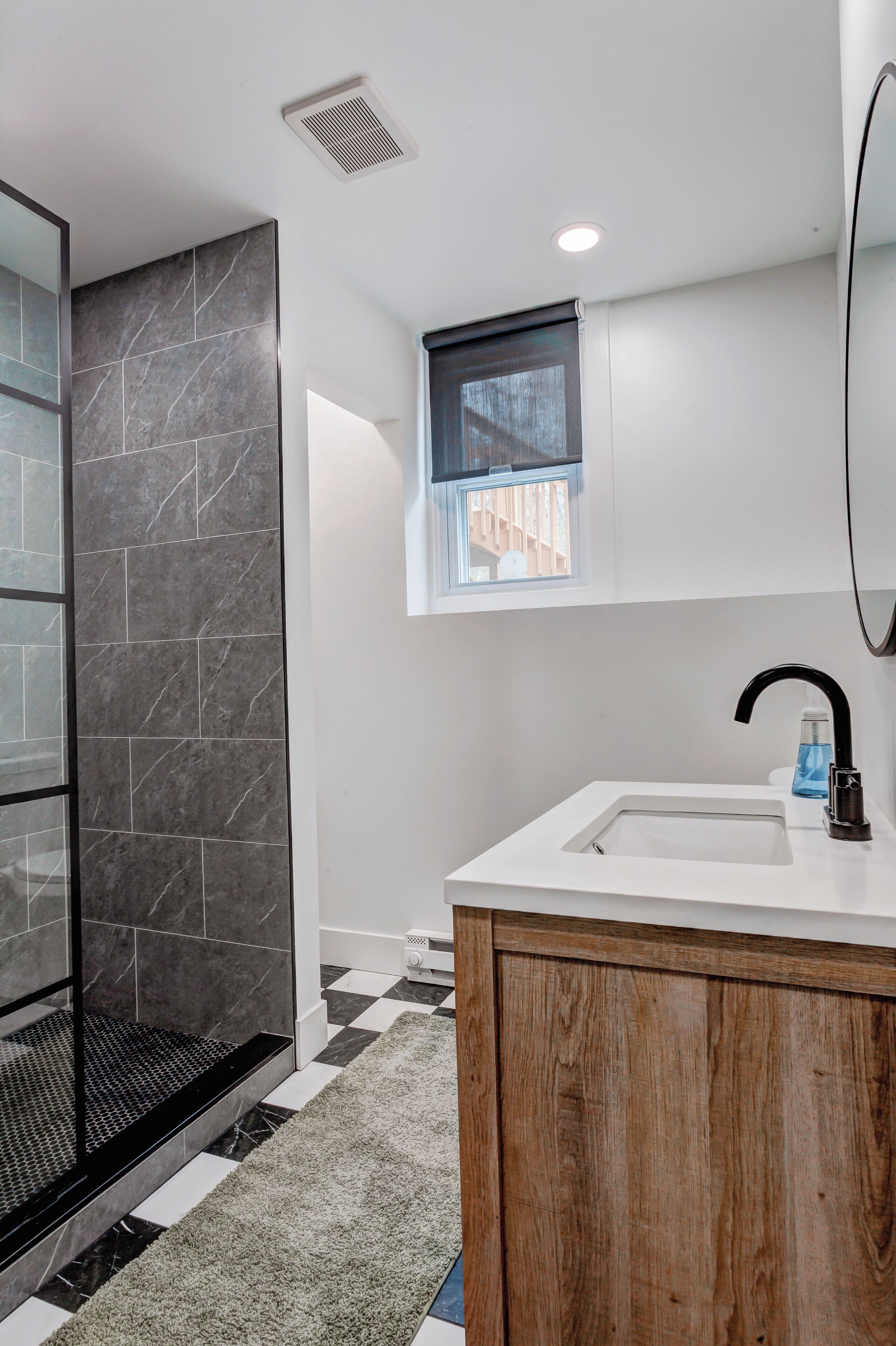 Un baño con ducha, lavabo, ventana y un armario de madera.