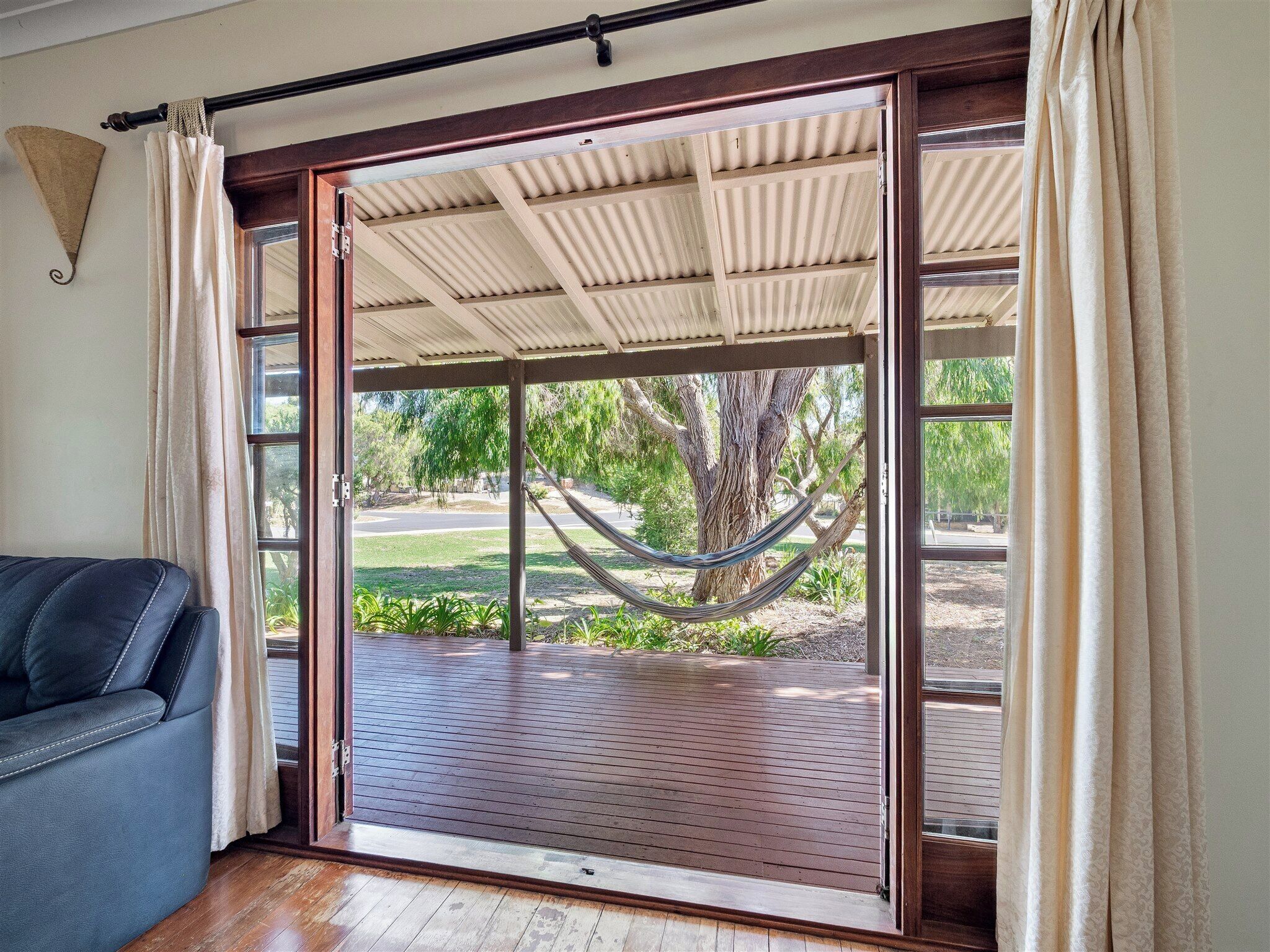 A room with a sliding glass door leading to an outdoor deck with a hammock.